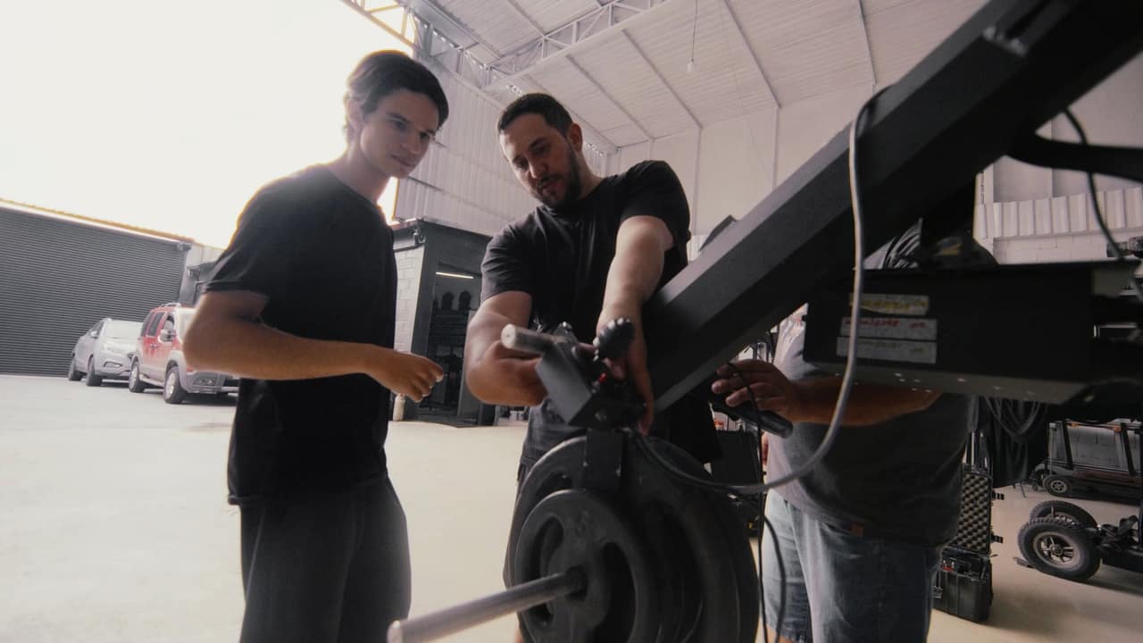 Profissionais examinando e ajustando um equipamento de movimento de câmera no galpão.